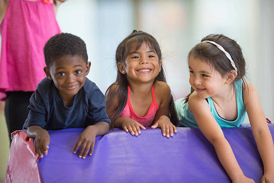 Three children smiling during an indoor gymnastics class