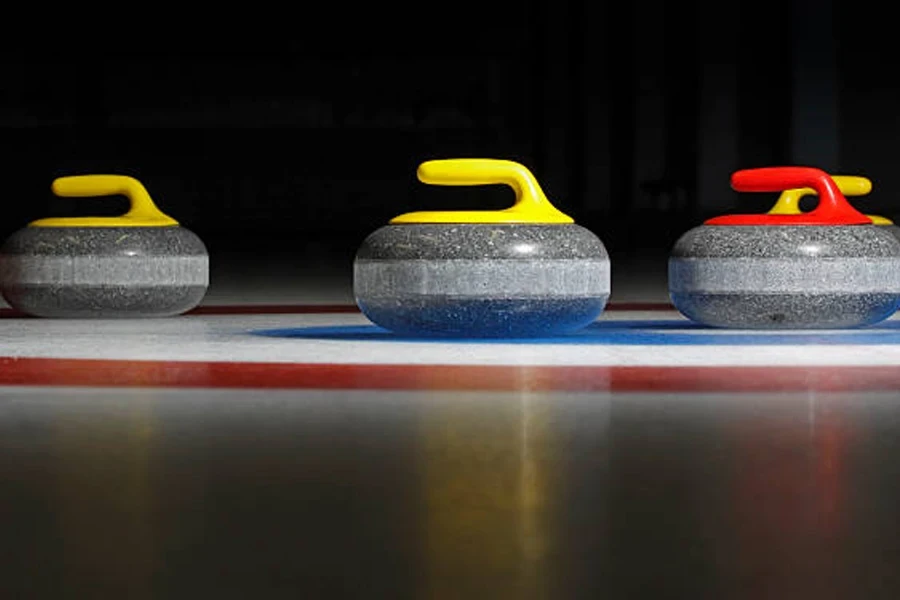 Tre pietre da curling allineate sulla pista di pattinaggio