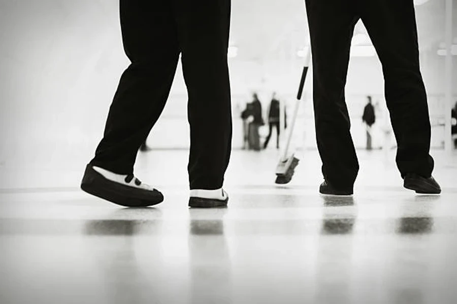 Due bigodini che indossano scarpe da curling bianche e nere sul ghiaccio