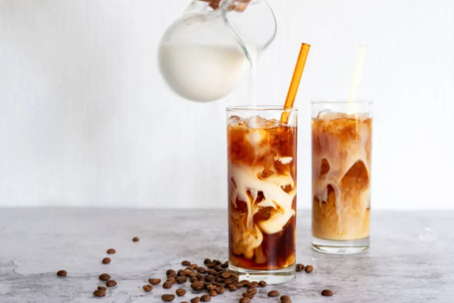 Two glasses of cold coffee with a few coffee beans lying around