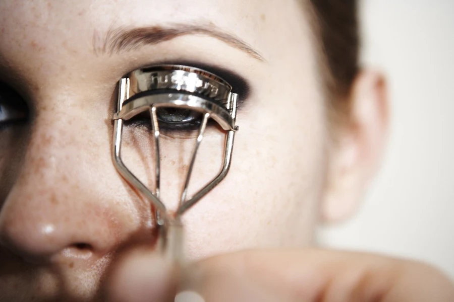 Woman closing her eyes using eyelash curlers