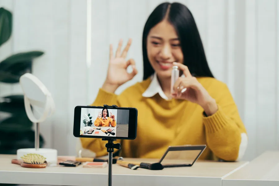 Mujer creando un vlog de maquillaje con su teléfono