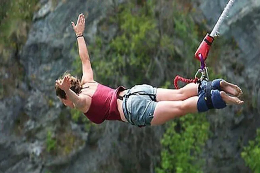 Wanita melompat sambil diikatkan pada tali pengaman pergelangan kaki