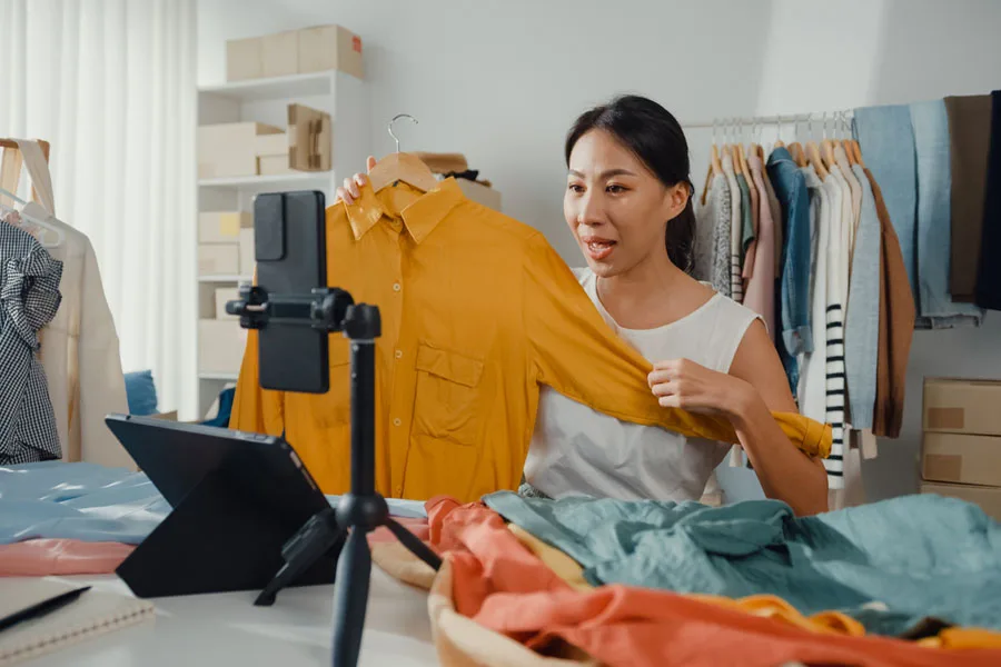 Mulher transmitindo ao vivo para vender roupas online enquanto está em casa