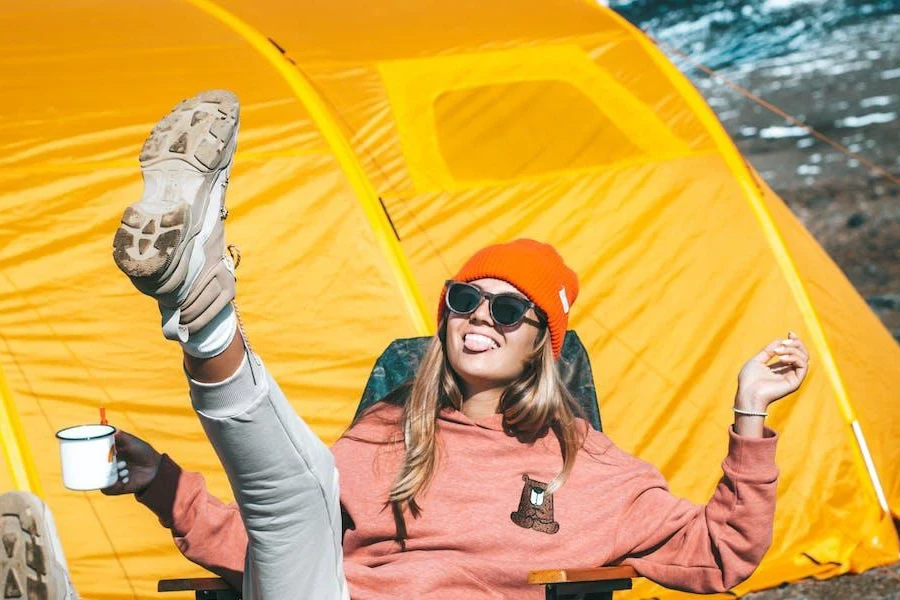 Woman looking playful in front of a yellow tunnel tent