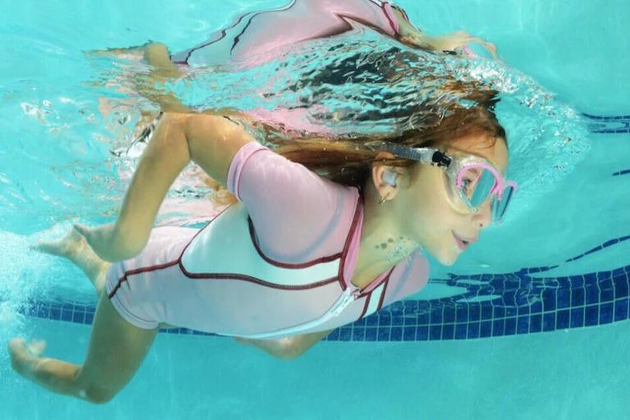 Mulher nadando enquanto usa protetores de ouvido