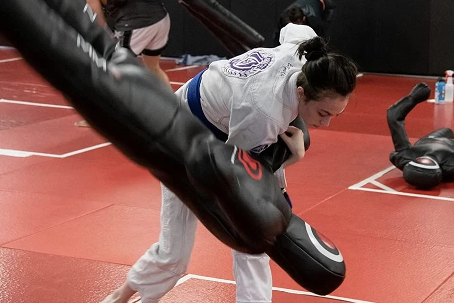 Woman taking down a black wrestling dummy