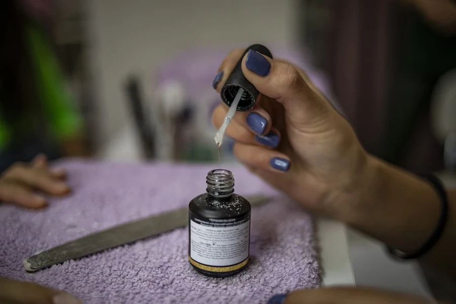 Frau benutzt eine Flasche Nagelkleber