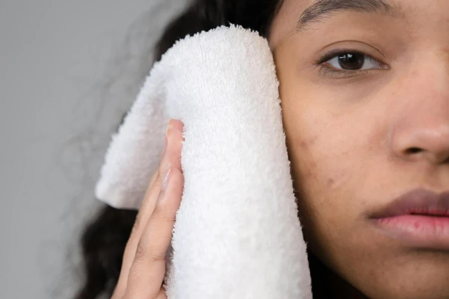 Femme utilisant une serviette blanche pour le visage