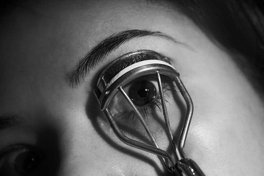 Woman using eyelash curlers on her lashes