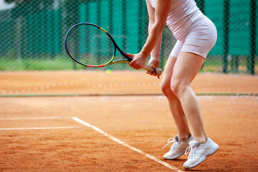 Mujer vistiendo tenis blancos ligeros en cancha de arcilla roja