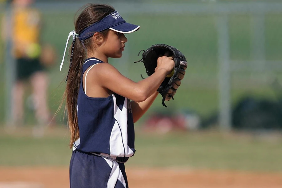 ソフトボールのミットを使用する青い服を着た若い女の子
