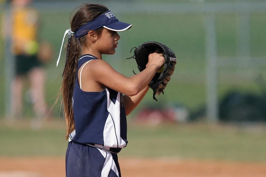 Chica joven en azul usando guante de softbol