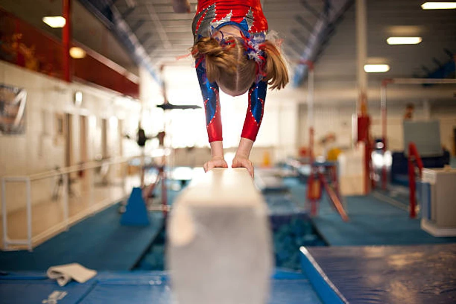 Young girl performing routine on white gymnastics beam