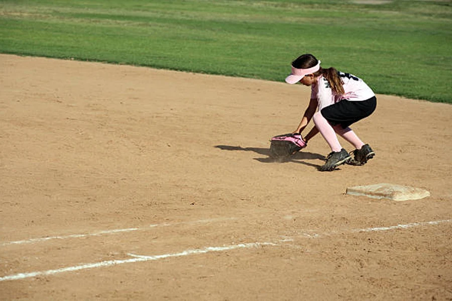 Gadis muda mengambil softball mengenakan celana pendek softball hitam