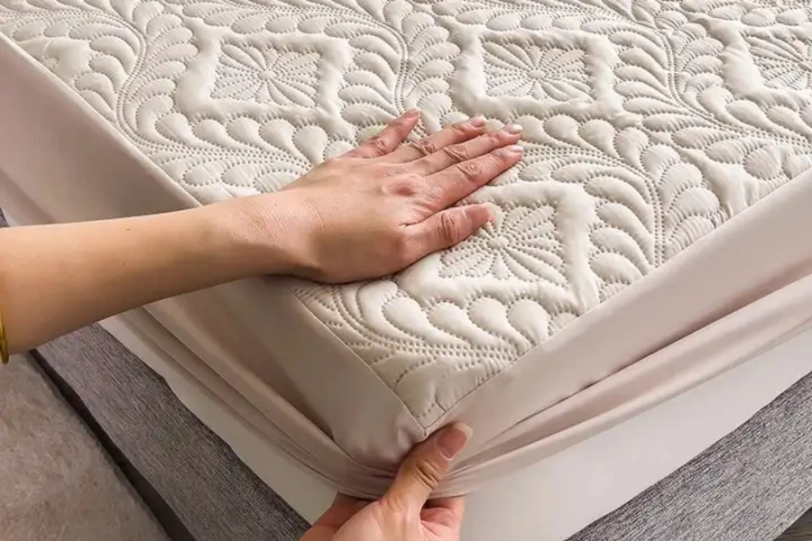 Cream-colored, patterned mattress protector fitted on a bed