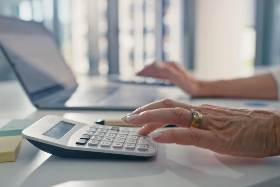 Finanza, contabilità o operazioni bancarie con una donna anziana che pianifica su una calcolatrice