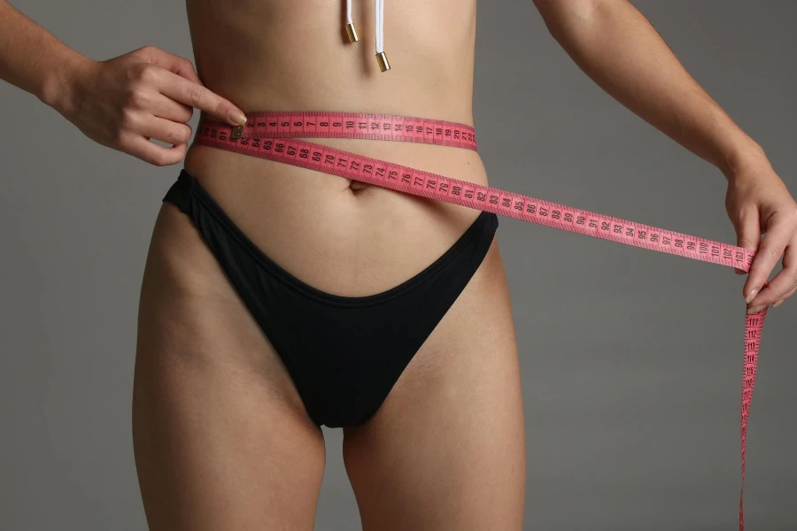 A Person Wearing Black Panty Holding Pink Tape Measure