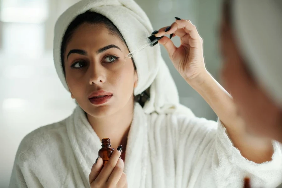 Young woman applying vitamin C serum