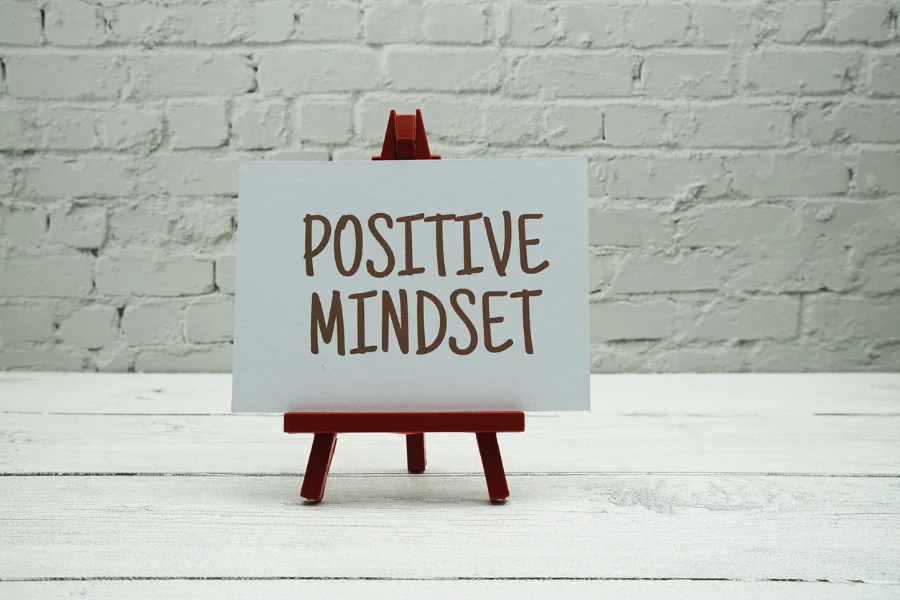 Positive Mindset text on white brick wall and wooden background