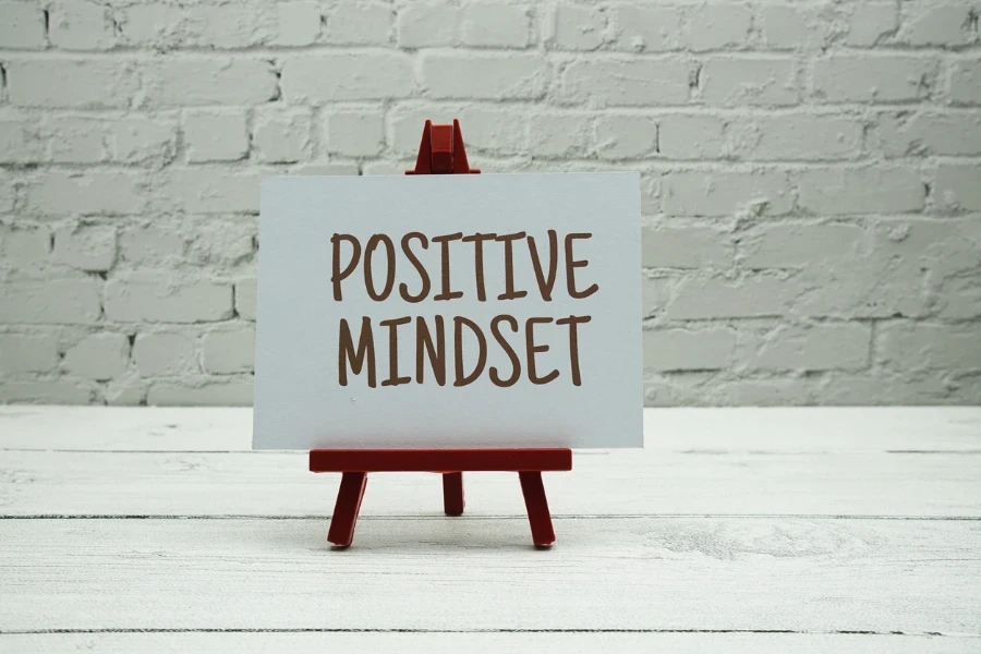 Positiver Mindset-Text auf weißer Ziegelwand und Holzhintergrund