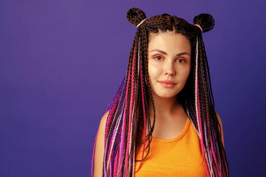 Mujer joven sonriente y positiva con coloridas trenzas africanas