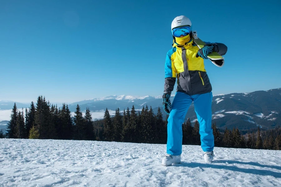 Porträt einer Skifahrerin mit Ski auf dem Gipfel der Berge, Winterurlaub