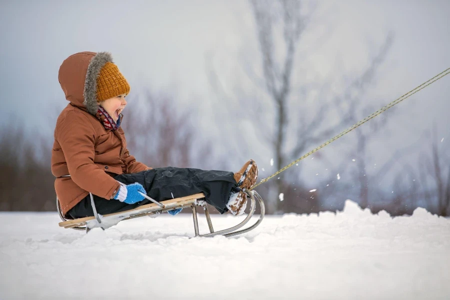 Une émotion très joyeuse d'un enfant lorsqu'il fait du traîneau sur de la neige duveteuse