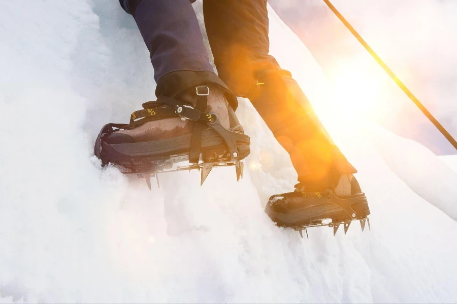 Gros plan d'un grimpeur escaladant une montagne de glace en crampons