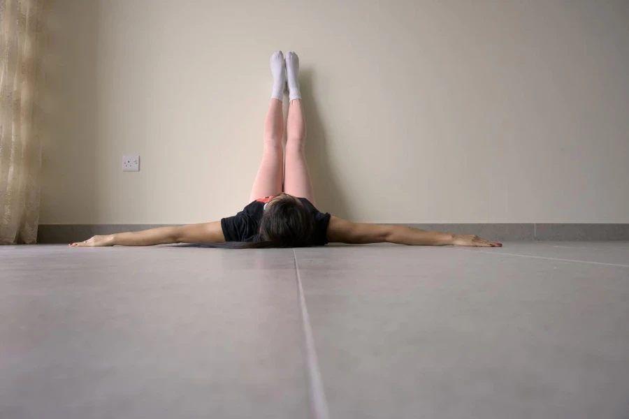 Femme allongée sur le sol, relaxant les pieds sur fond de mur