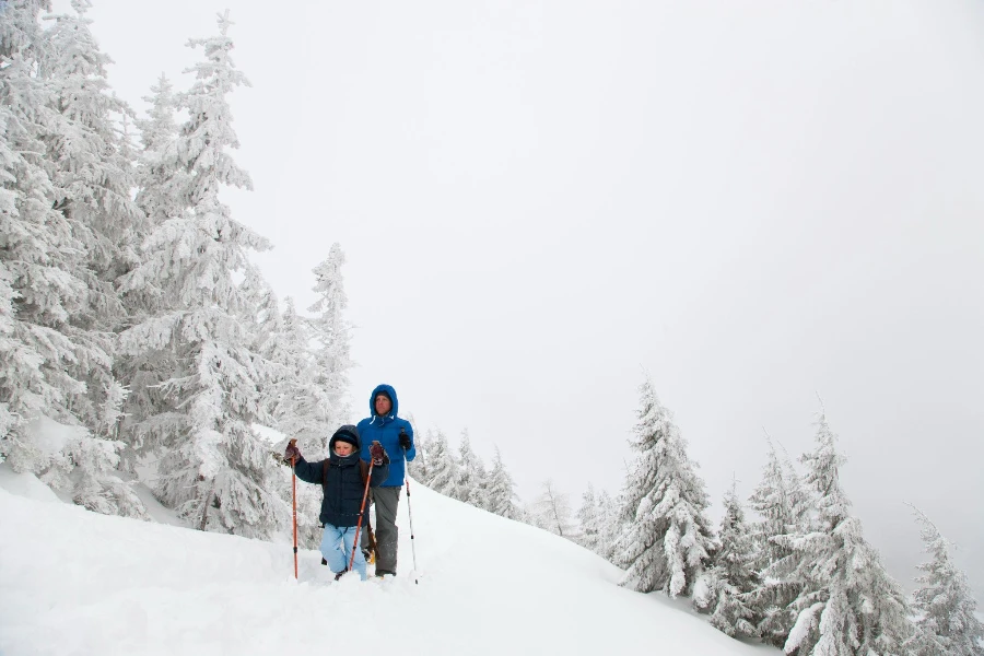 Vater und Sohn beim Schneeschuhwandern am Hang