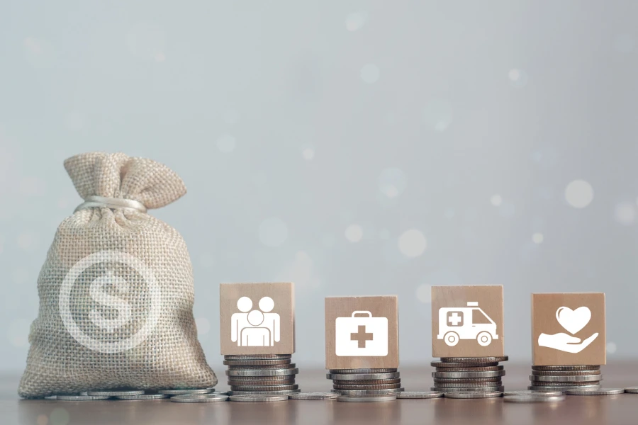 Koin uang dan balok kayu ditumpuk dengan ikon medis kesehatan