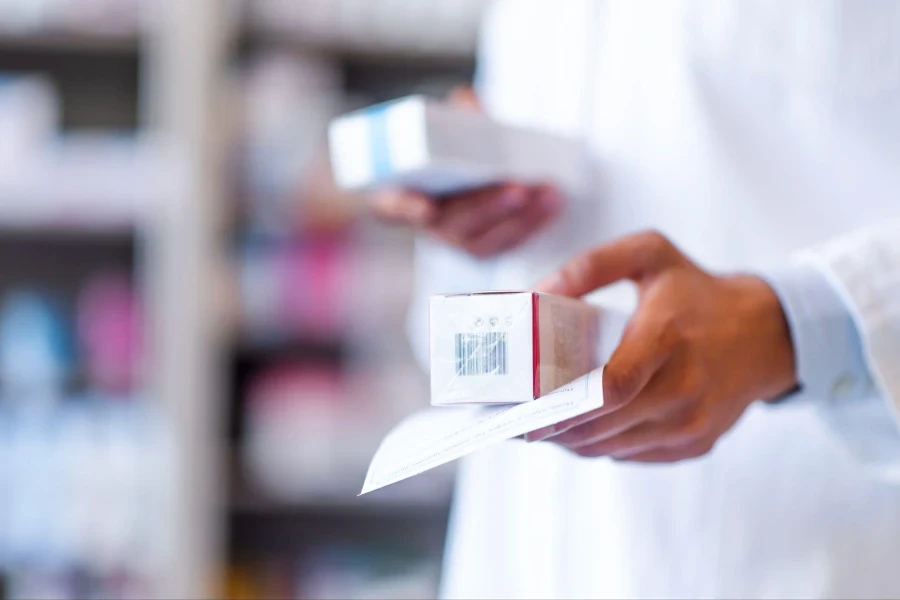 Mano de cerca de una farmacéutica con receta y medicamentos en la farmacia.