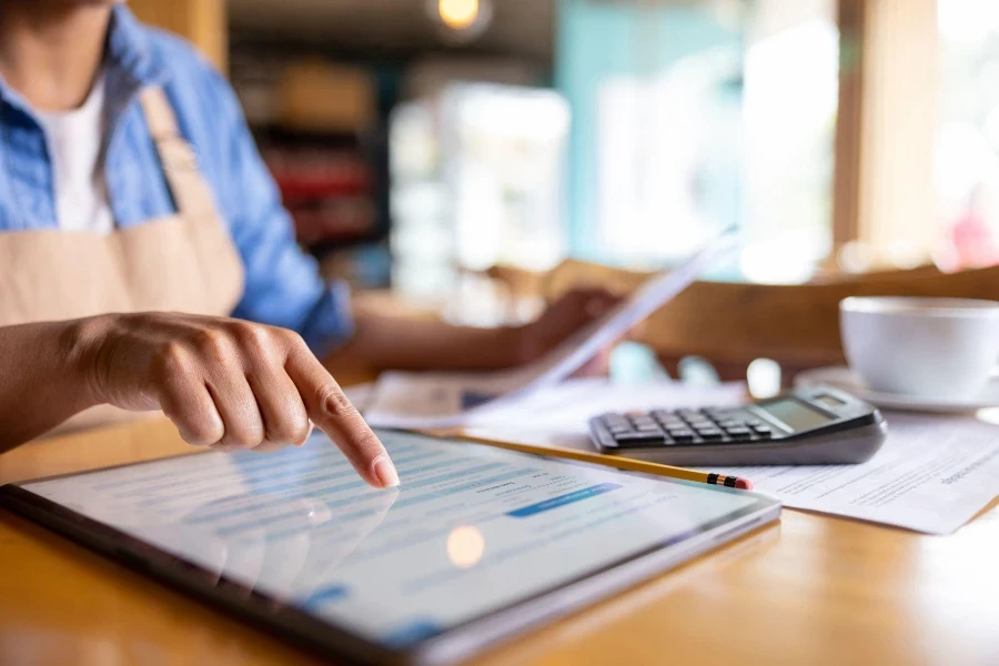 Close de um empresário fazendo contabilidade em um café usando um tablet