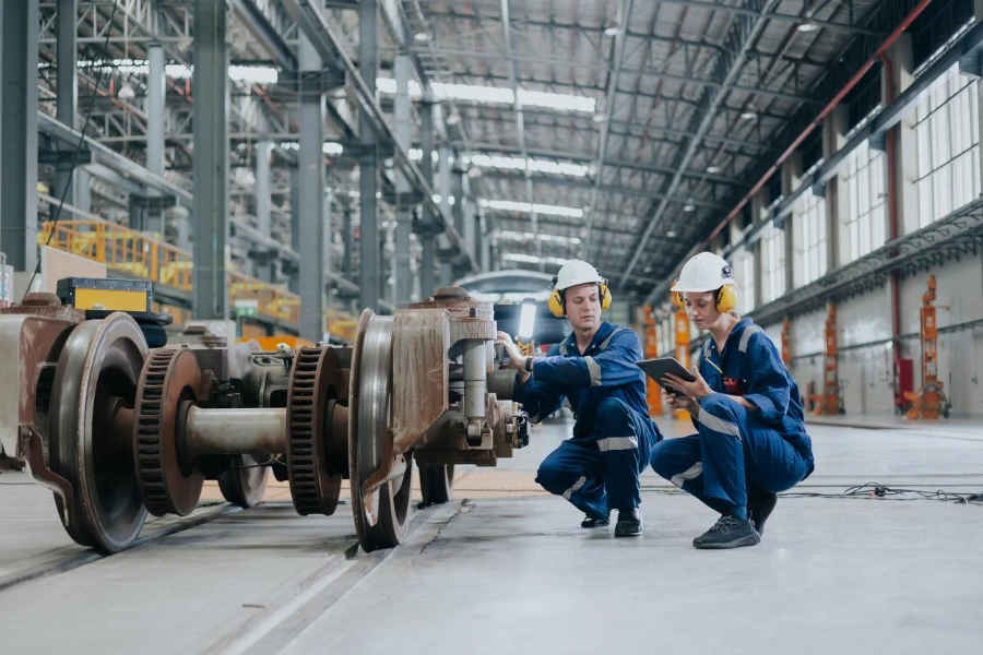 Equipo de ingenieros trabajando servicio de mantenimiento reparación reemplazar rueda de tren en depósito de reparación de locomotoras