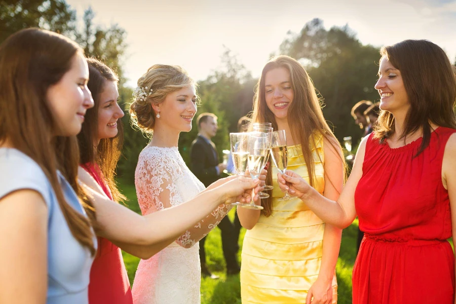 外の結婚披露宴で乾杯する4人の幸せなブライズメイドと花嫁