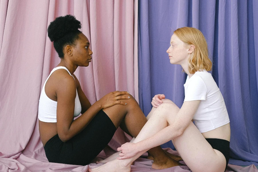 Women in White Tops Sitting on the Floor Face to Face