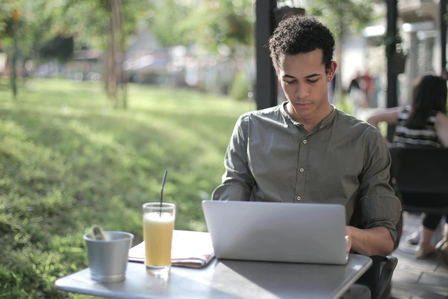 Pekerja lepas pria kulit hitam terfokus menggunakan laptop di kafe jalanan