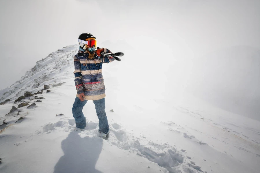 Plan complet d'une skieuse joyeuse portant ses skis sur son épaule