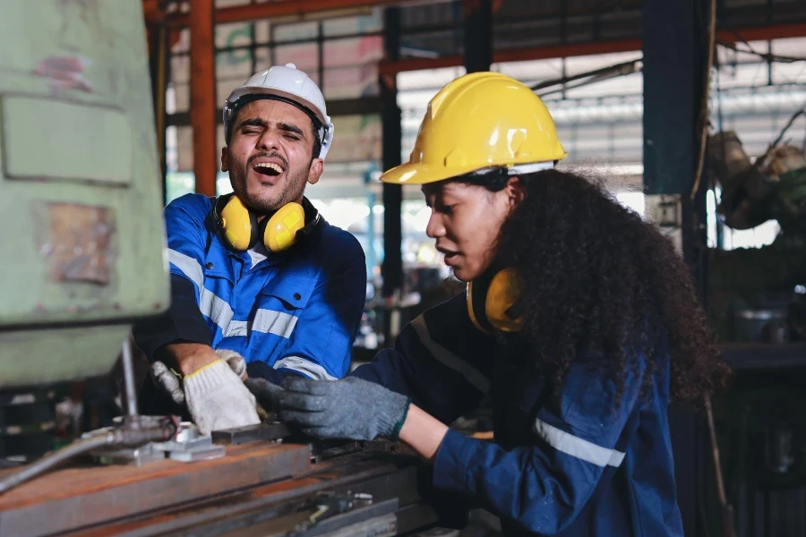 Junger Techniker in Schutzuniform hatte einen Handunfall an einer Drehmaschine in einer Metalldrehmaschine.