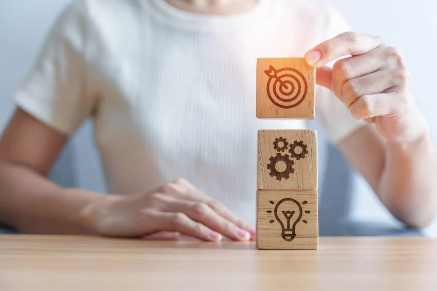 Woman hand holding dartboard above Gear and Lightbulb icon block