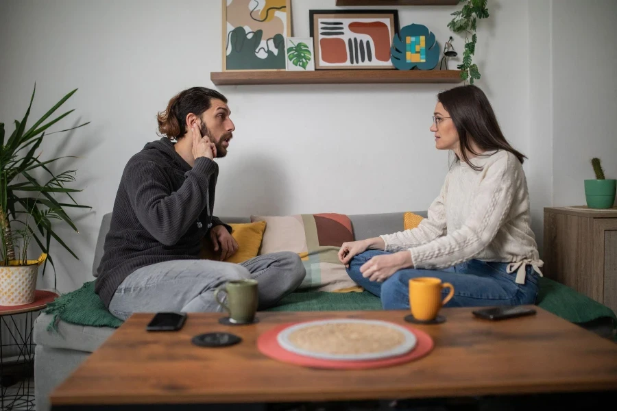 Dois jovens surdos estão sentados em casa e falando em linguagem de sinais.