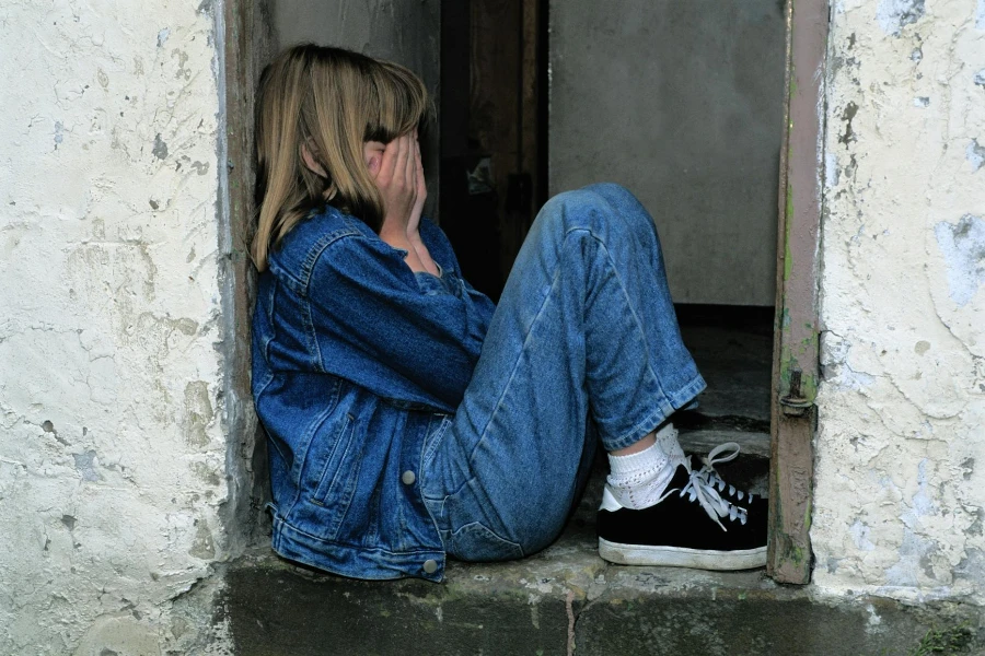 Chica solitaria sentada en una puerta