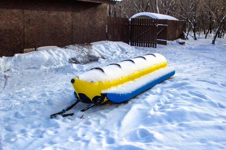 An einem klaren Frühlingstag mit einem Schaumstoffschlitten im Schnee fahren