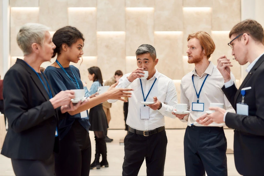 İş konferansında kahve molası sırasında etkileşime giren bir grup iş adamı.