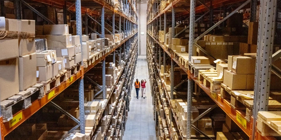 High angle view of a warehouse manager walking with foremen checking stock on racks