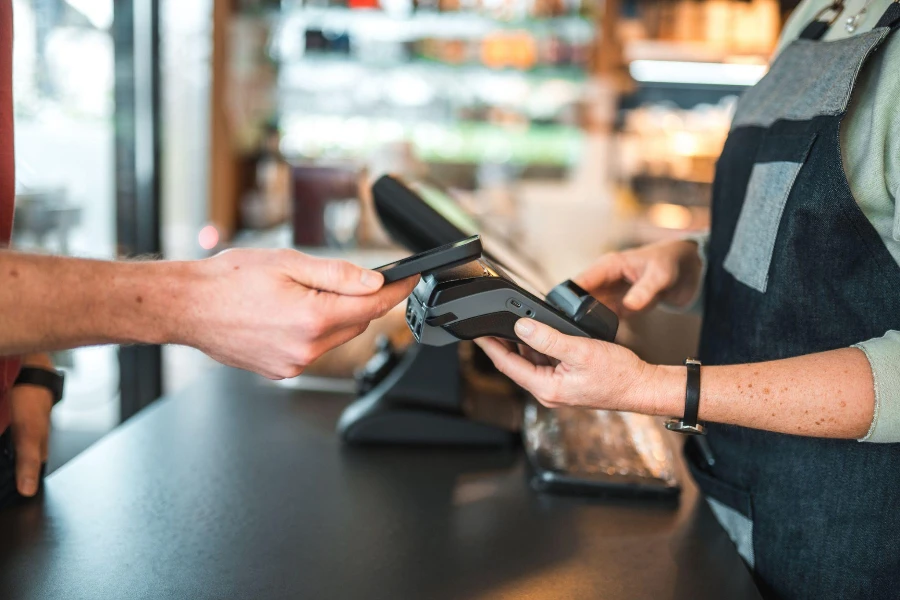 Close up of hands of a Caucasian barmaid holding a POS terminal