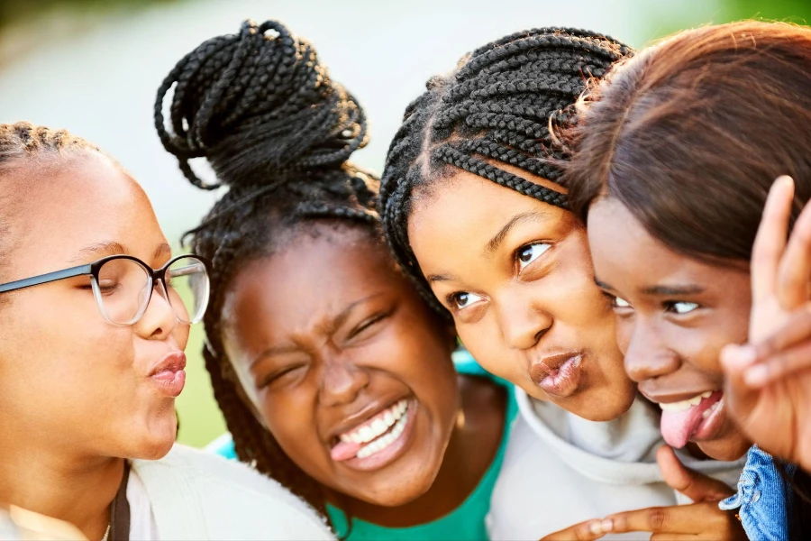 屋外で変な顔をする 4 人のアフリカの 10 代の女の子のクローズ アップ