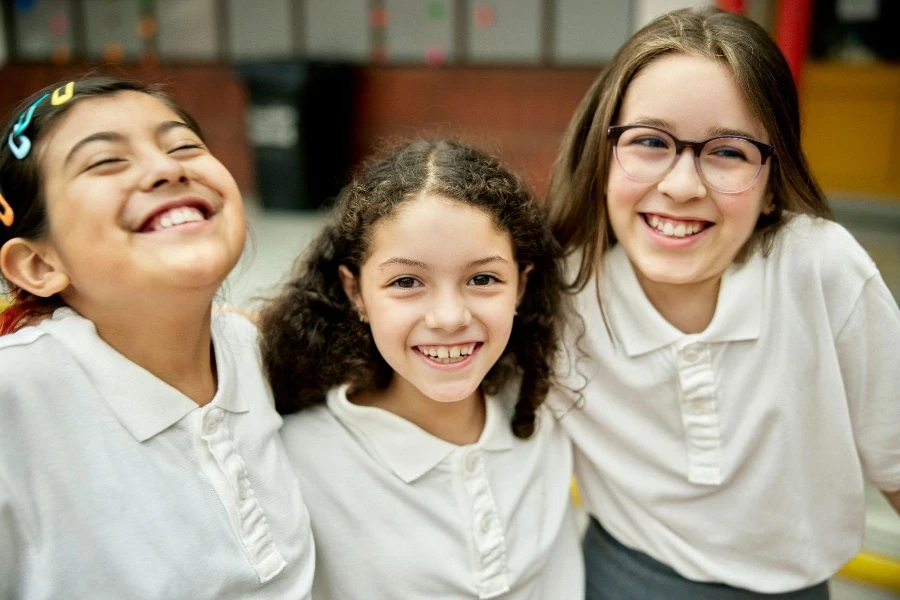 Vista de cintura para arriba de amigos de 9 y 11 años de pie con uniformes iguales