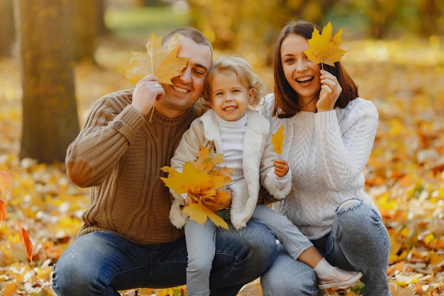 Familia alegre divirtiéndose con hojas de otoño